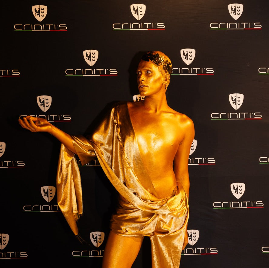 Gold statue of a draped figure against a branded backdrop