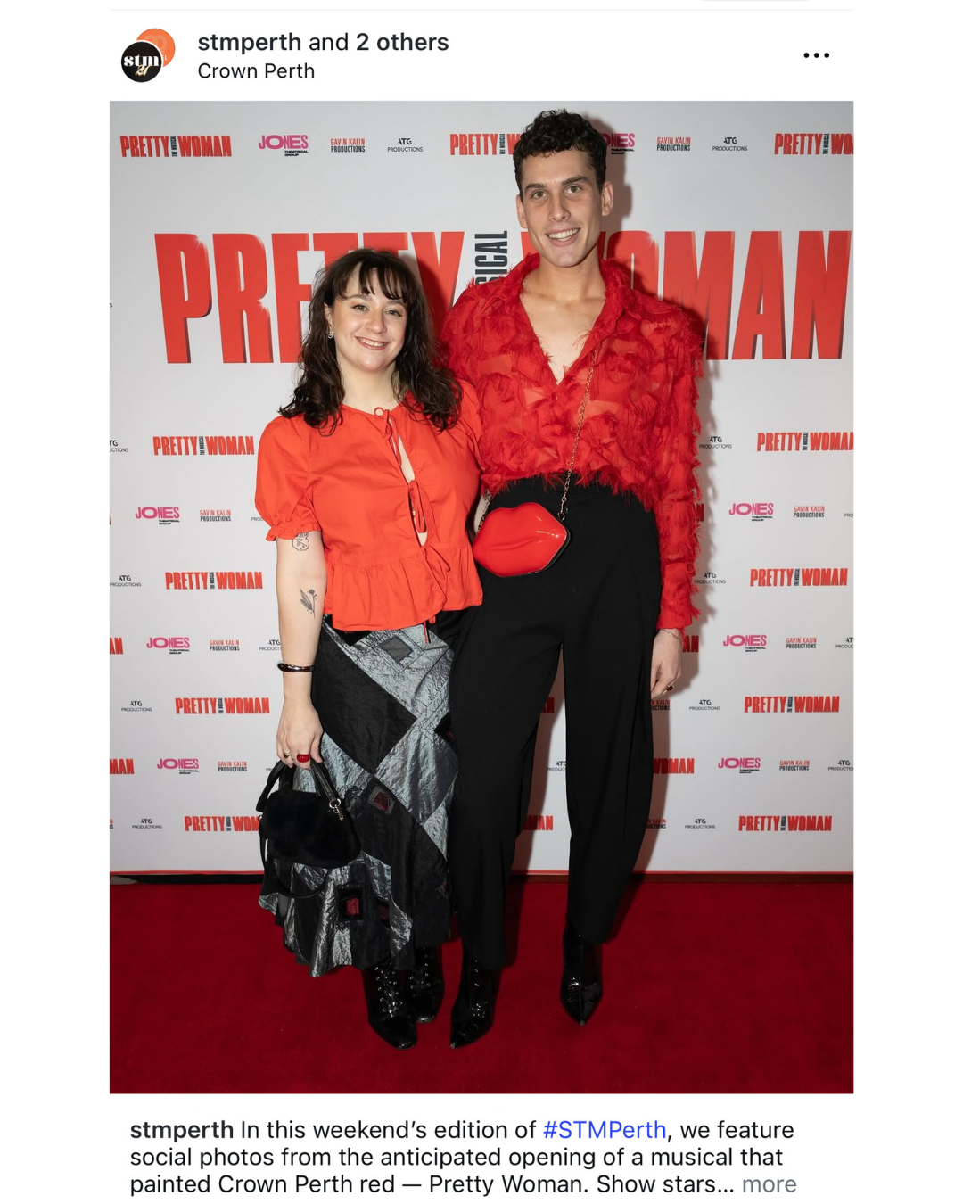 Two people posing on a red carpet with 'Pretty Woman' promotional backdrop