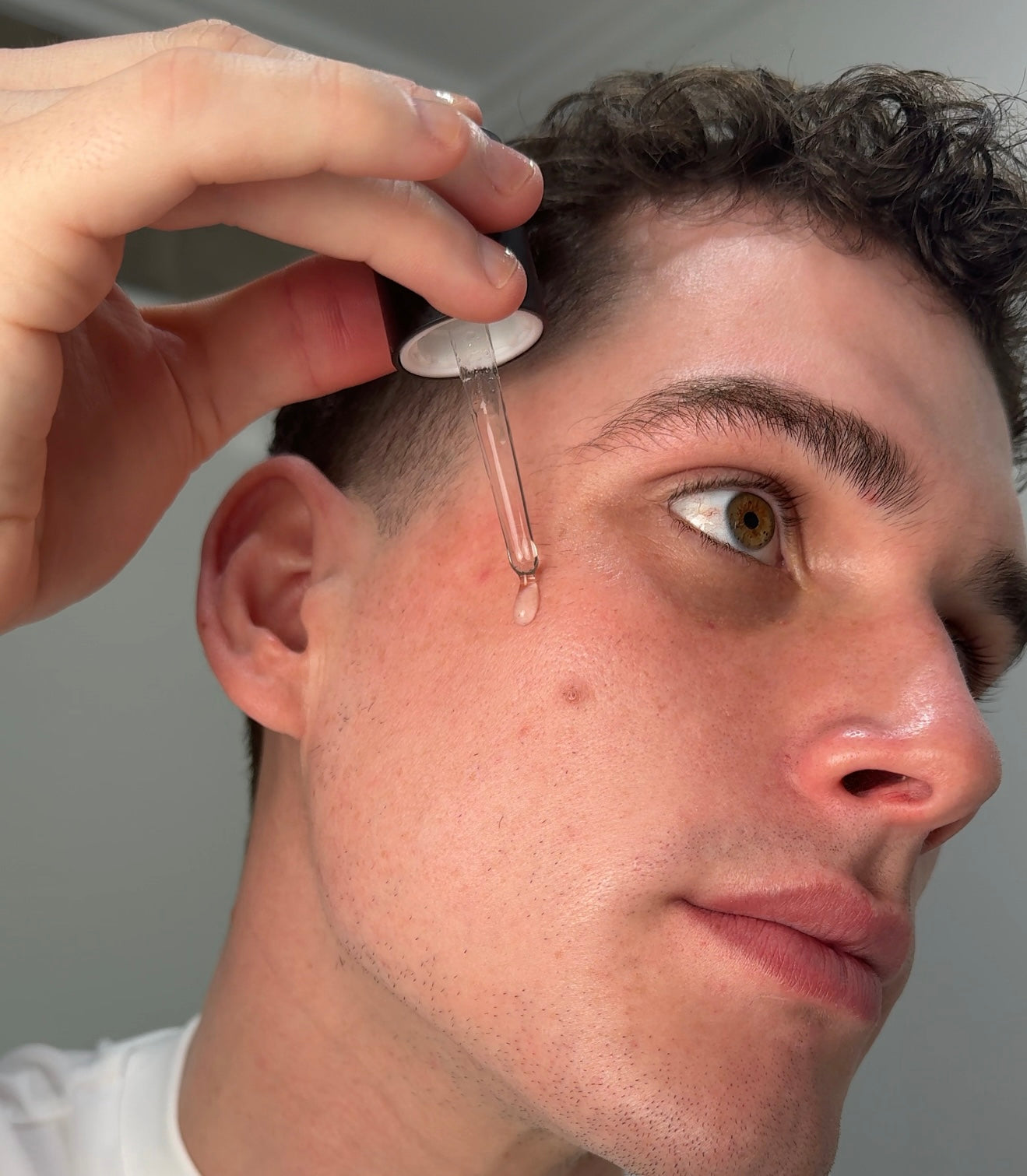 Close-up of a person applying a small device to another person's head.