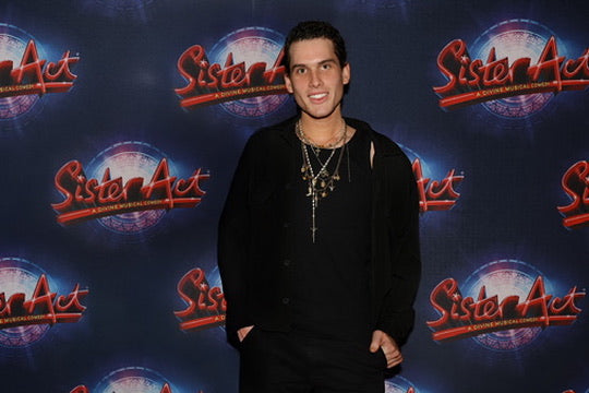 Person standing in front of a 'Sister Act' themed backdrop